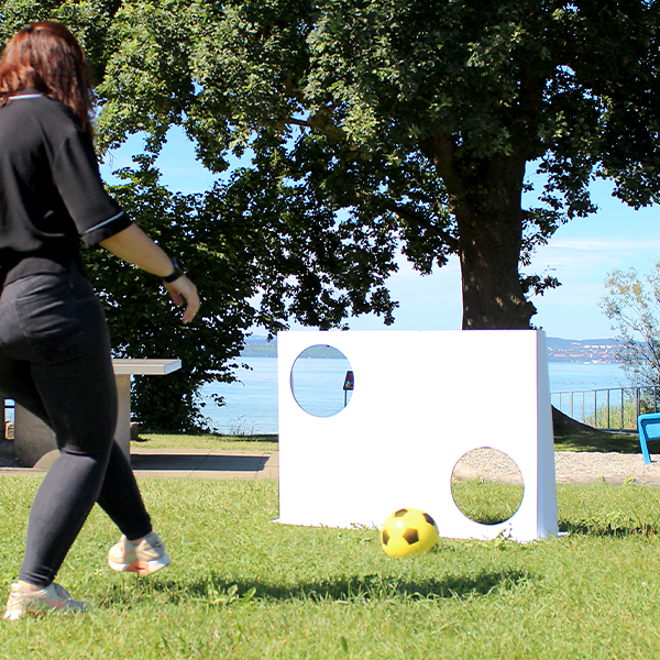 Frau spielt mit unbedruckter Torwand und Softball im Freien