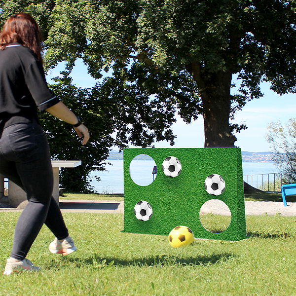 Frau spielt mit dem Torwandset mit Fussballmotiv im Freien