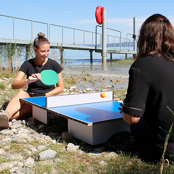 Zwei Frauen spielen Mini-Ping-Pong am See im Freien
